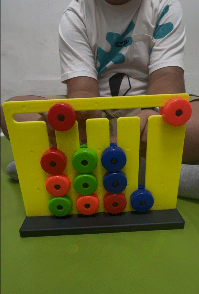 Child performing a color sorting and stacking activity to enhance fine motor skills at Jewel Autism Center, Dubai.